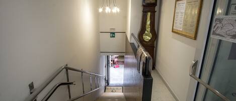 Interior de un hotel con una escalera, un reloj y un menú enmarcado en la pared.