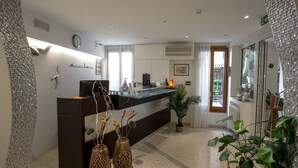 Un moderno vestíbulo de hotel con mostrador de recepción, jarrones decorativos y plantas en macetas.