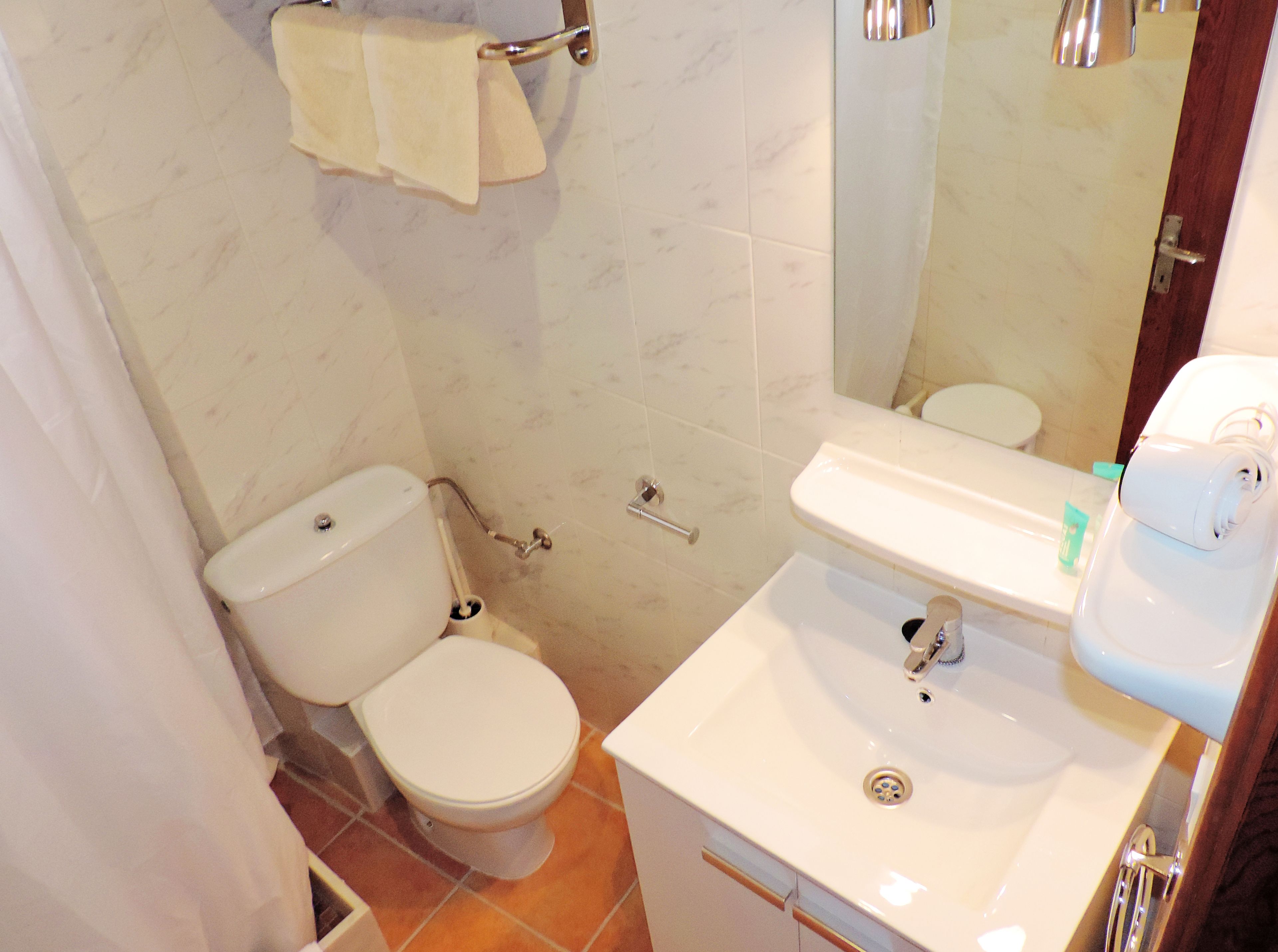 A bathroom with a toilet, sink, and mirror.