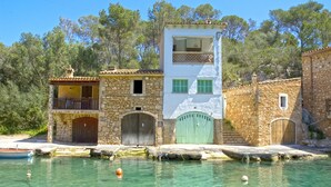 Un bâtiment situé sur la côte, avec des murs en pierre, un balcon et une vue dégagée sur la mer.