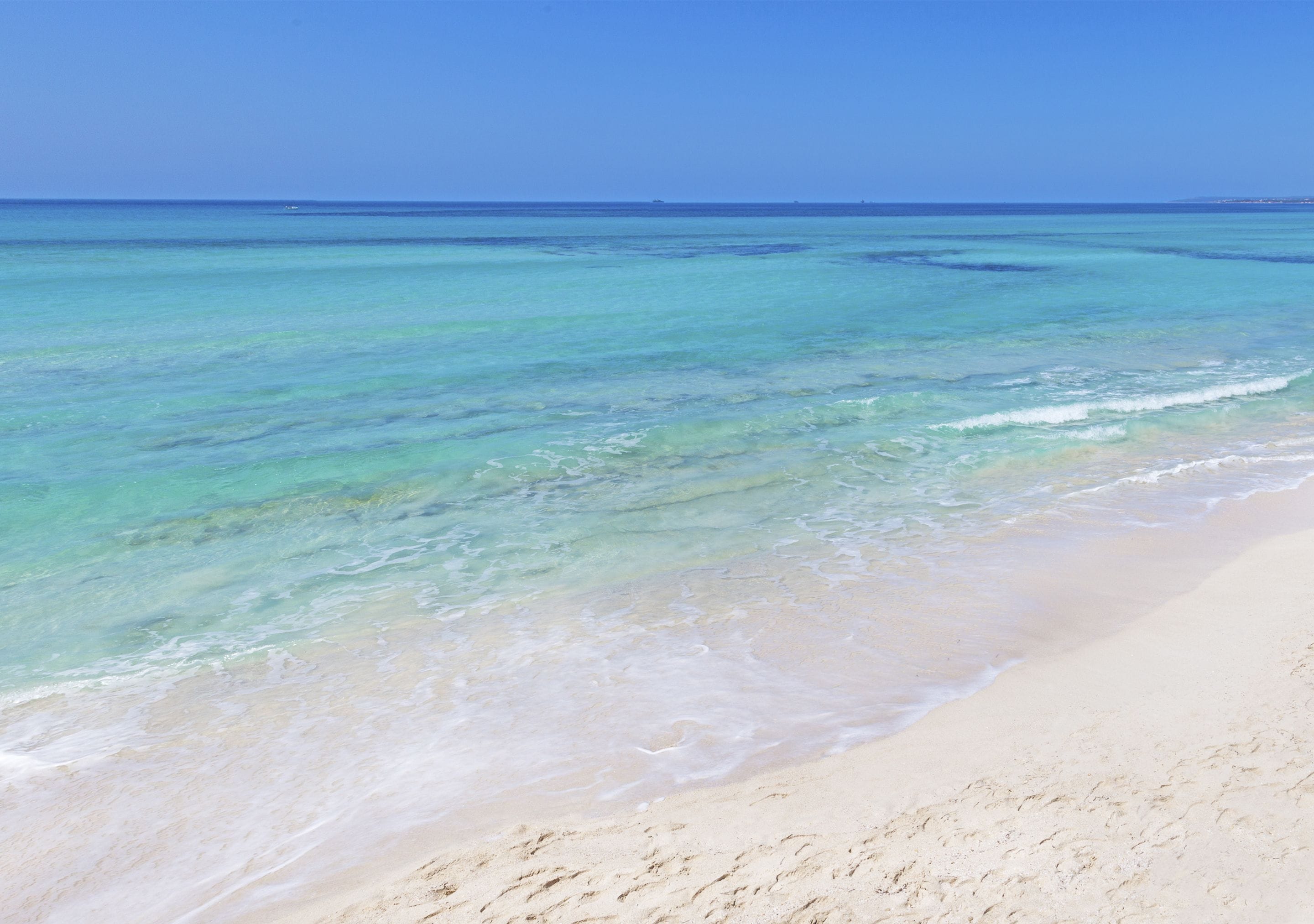 A beach with clear turquoise water and a sandy shore.
