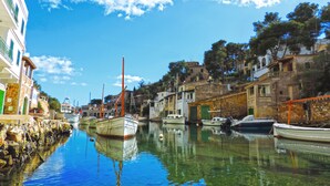 Un canal bordé de bateaux amarrés, des bâtiments le long de la rive et un ciel dégagé.