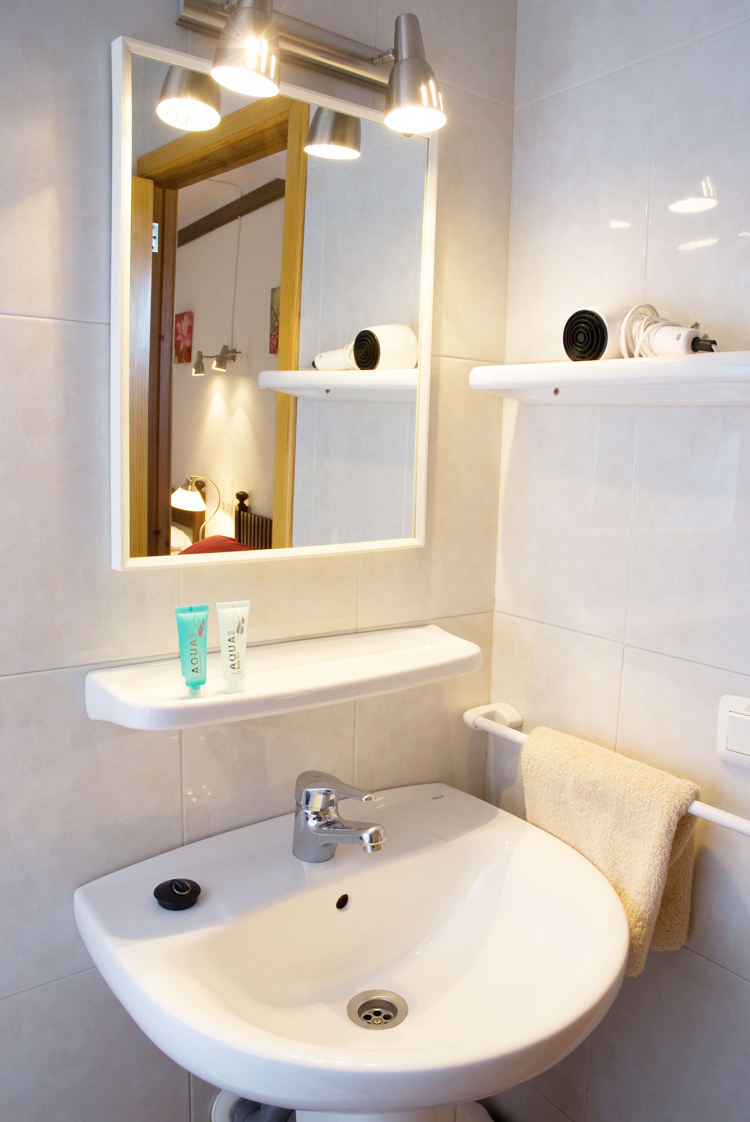 A bathroom with a white sink, mirror, and shelves.