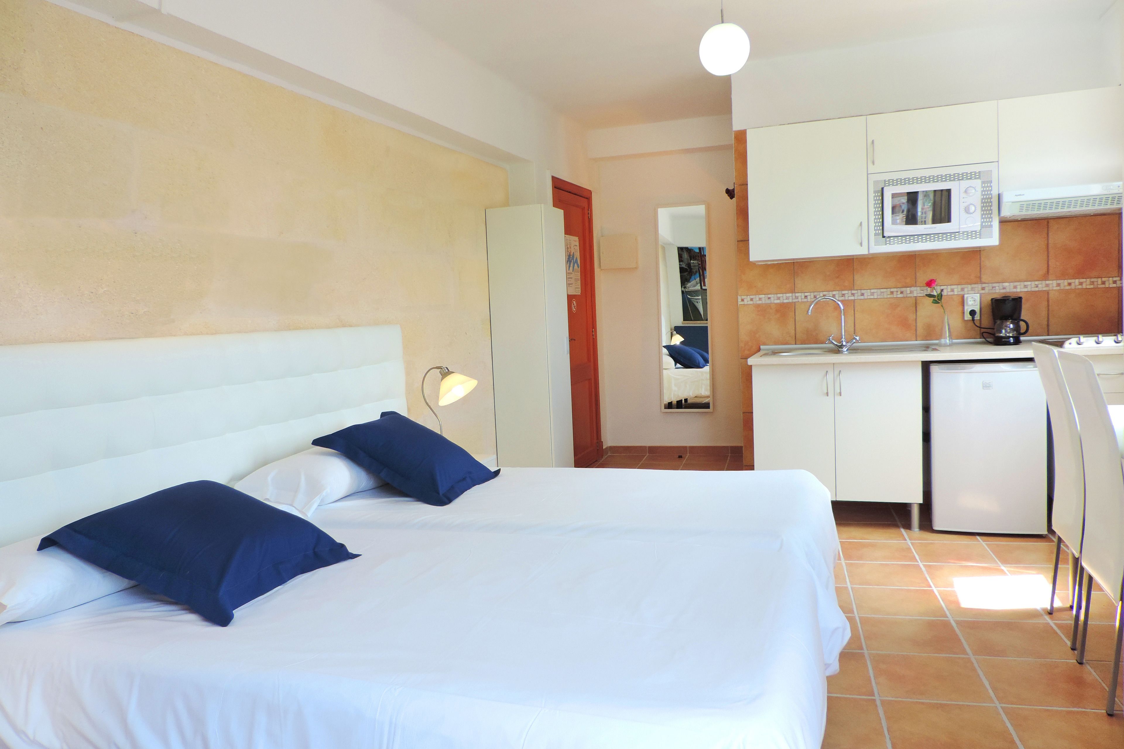 Ein Hotelzimmer mit Bett, Schreibtisch, Mikrowelle und Kaffeemaschine.