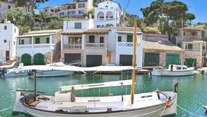 Un port de plaisance avec des bateaux amarrés, un immeuble doté de balcons et une colline parsemée d’arbres.