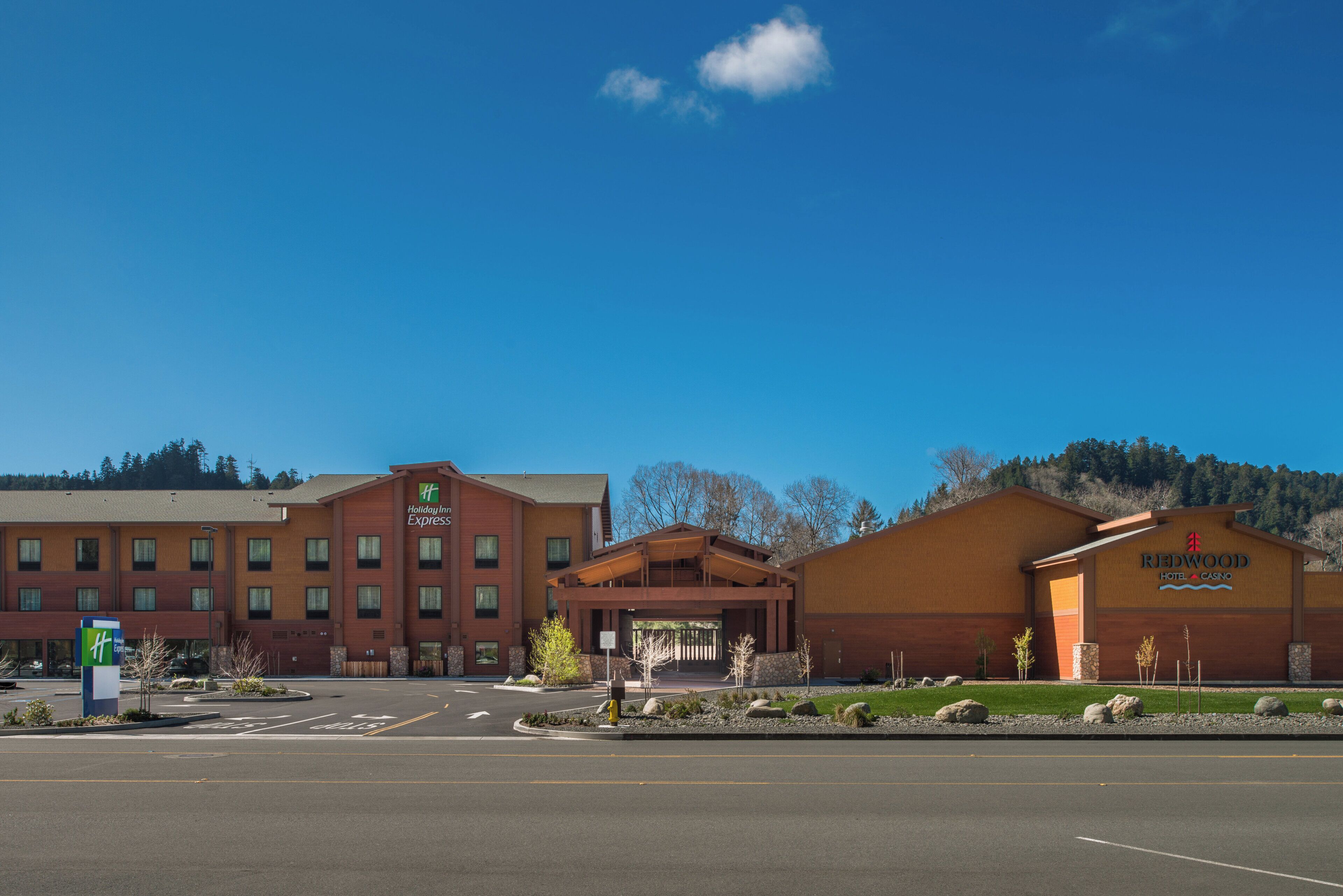 A Holiday Inn Express hotel with a modern brick facade, a separate building for the Redwood Hotel & Casino, and a parking lot in front.