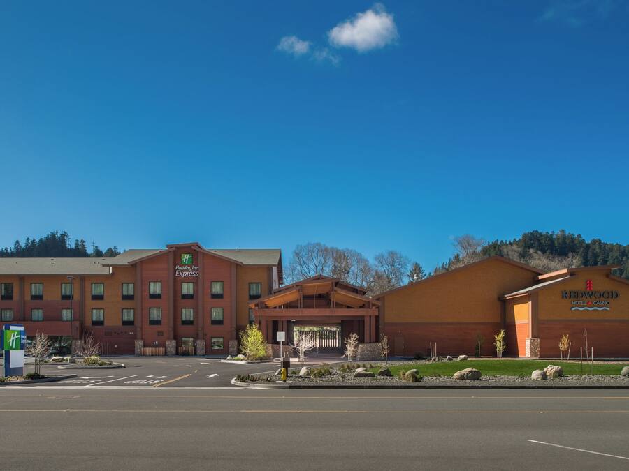 A Holiday Inn Express hotel with a modern brick facade, a separate building for the Redwood Hotel & Casino, and a parking lot in front.
