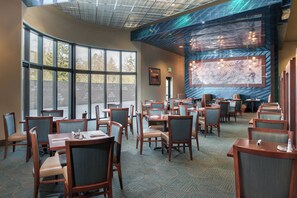 A hotel dining area with multiple tables and chairs, large windows, and a mural on the wall. - Holiday Inn Express Klamath - Redwood Ntl Pk Area by IHG (Klamath)