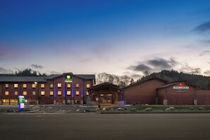 A Holiday Inn Express building with a brick facade, a separate Redwood Hotel Casino building, and a well-maintained parking lot. - Holiday Inn Express Klamath - Redwood Ntl Pk Area by IHG (Klamath)