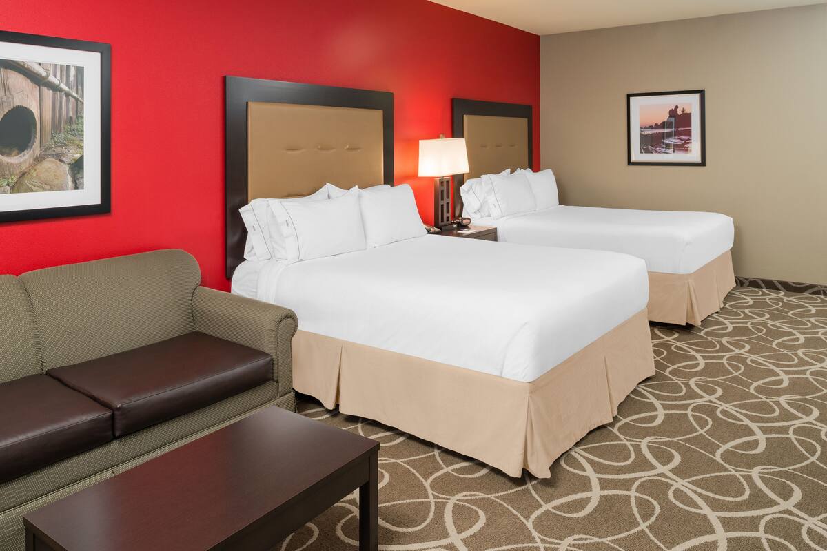 A hotel room with two beds, a sofa, a table, and a patterned carpet.