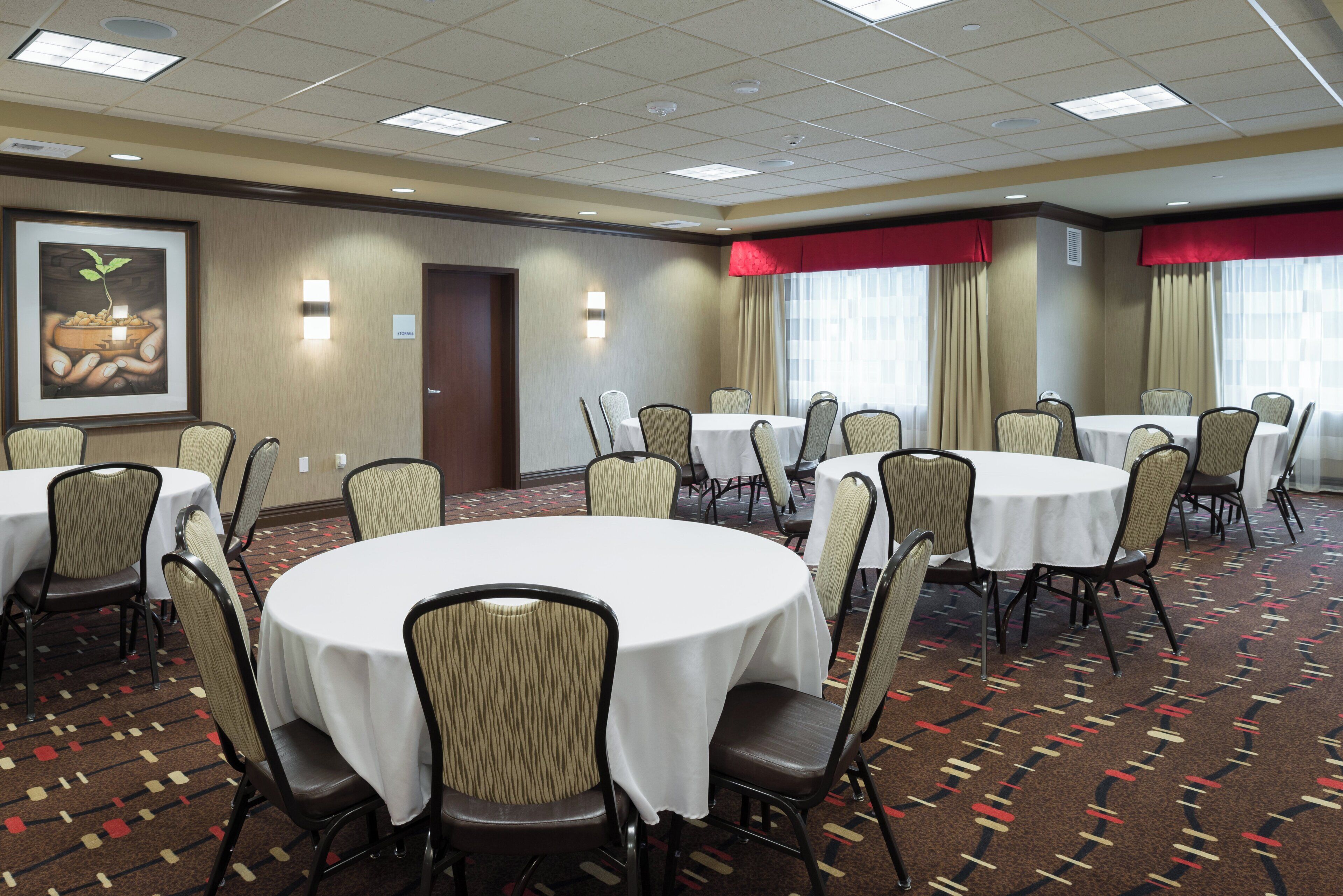A conference room with round tables, chairs, and a large framed picture on the wall.