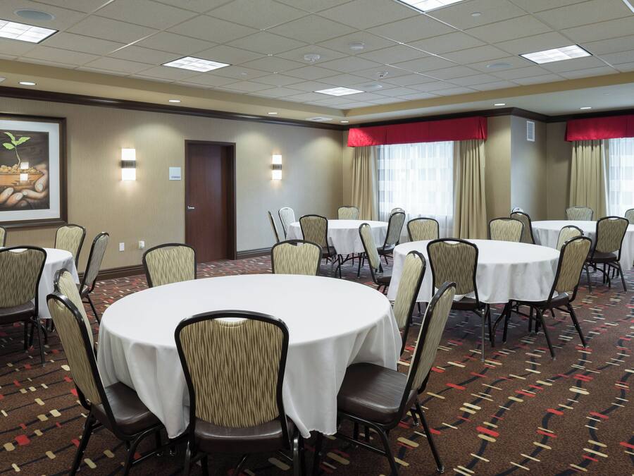 A conference room with round tables, chairs, and a large framed picture on the wall.