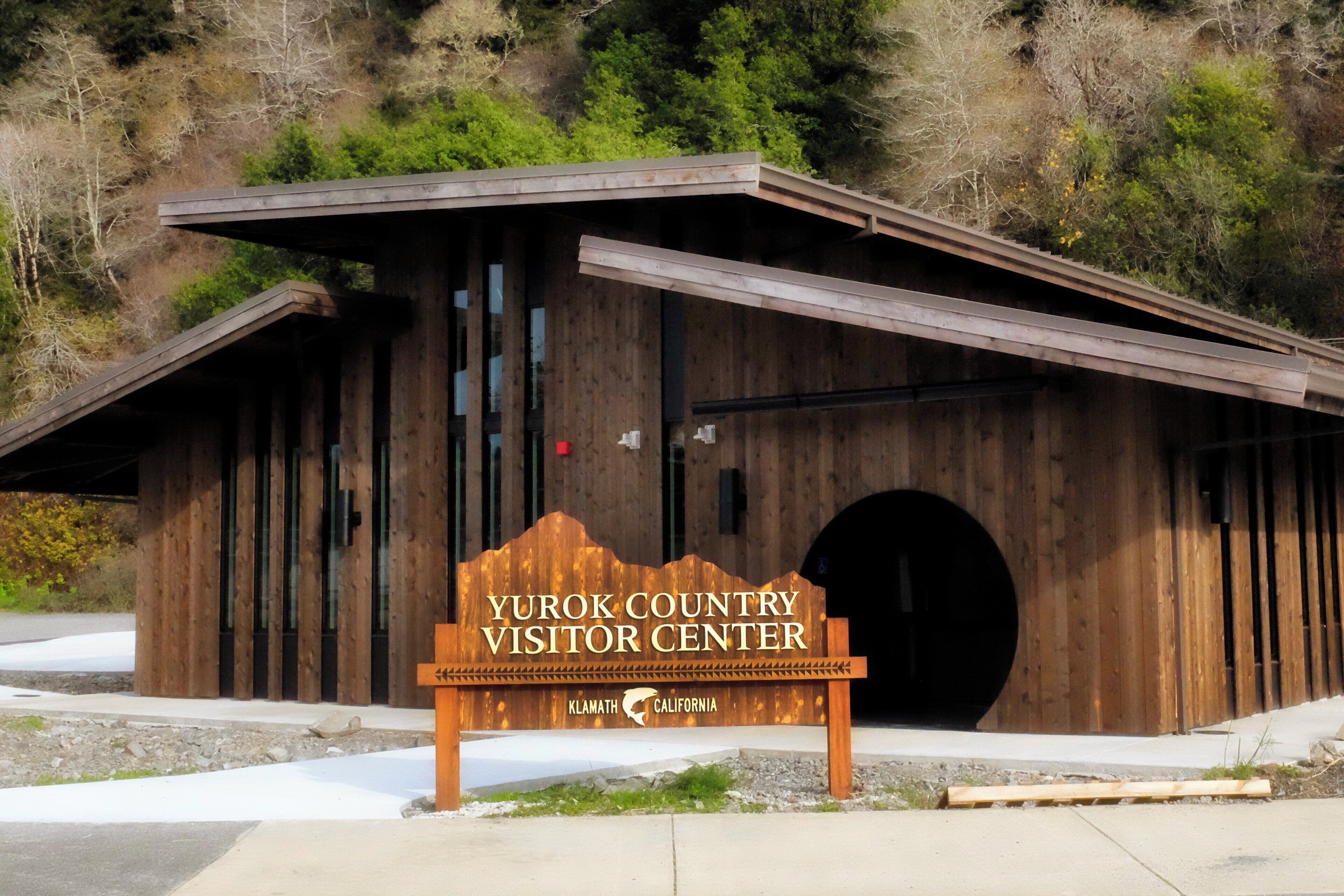 Un centro visitatori in legno con un cartello che recita 'Yu'rok Country Visitor Center' e 'Klamath California' sul lato.