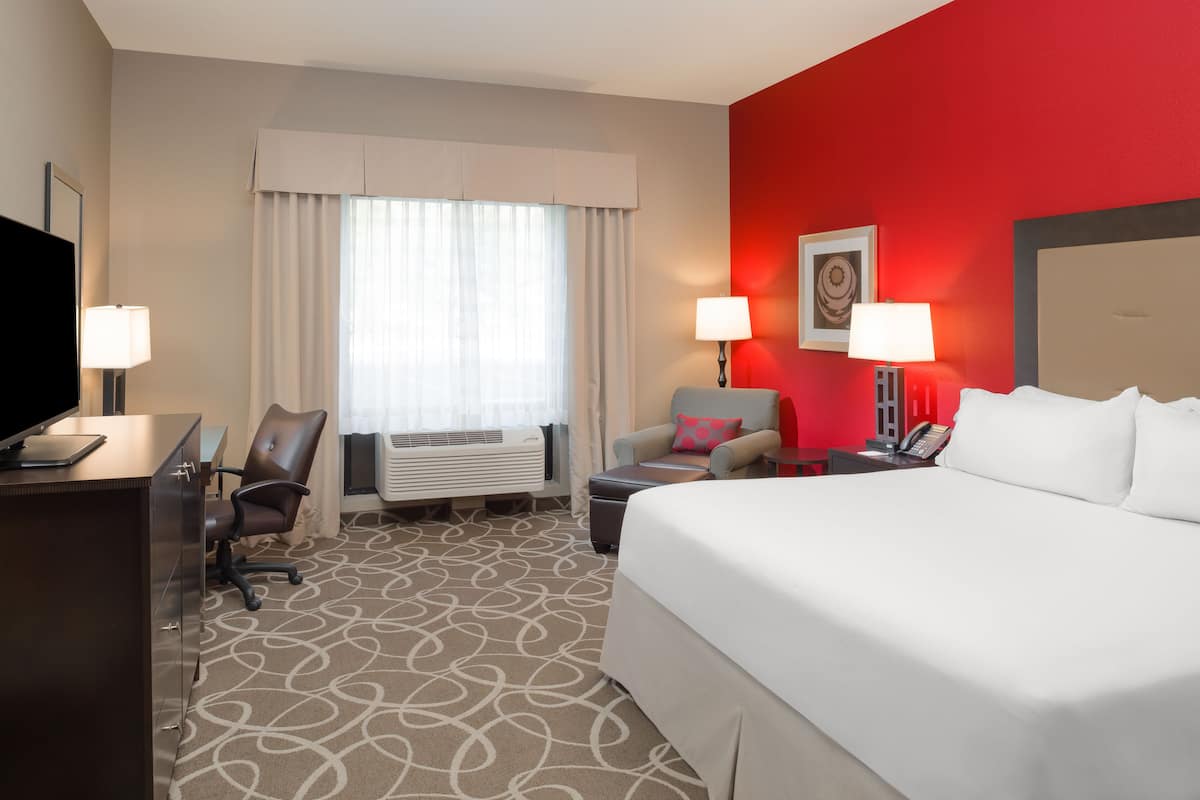 A hotel room with a bed, desk, chair, and two bedside lamps.