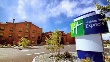 Señal de Holiday Inn Express con un cielo despejado y un edificio al fondo.