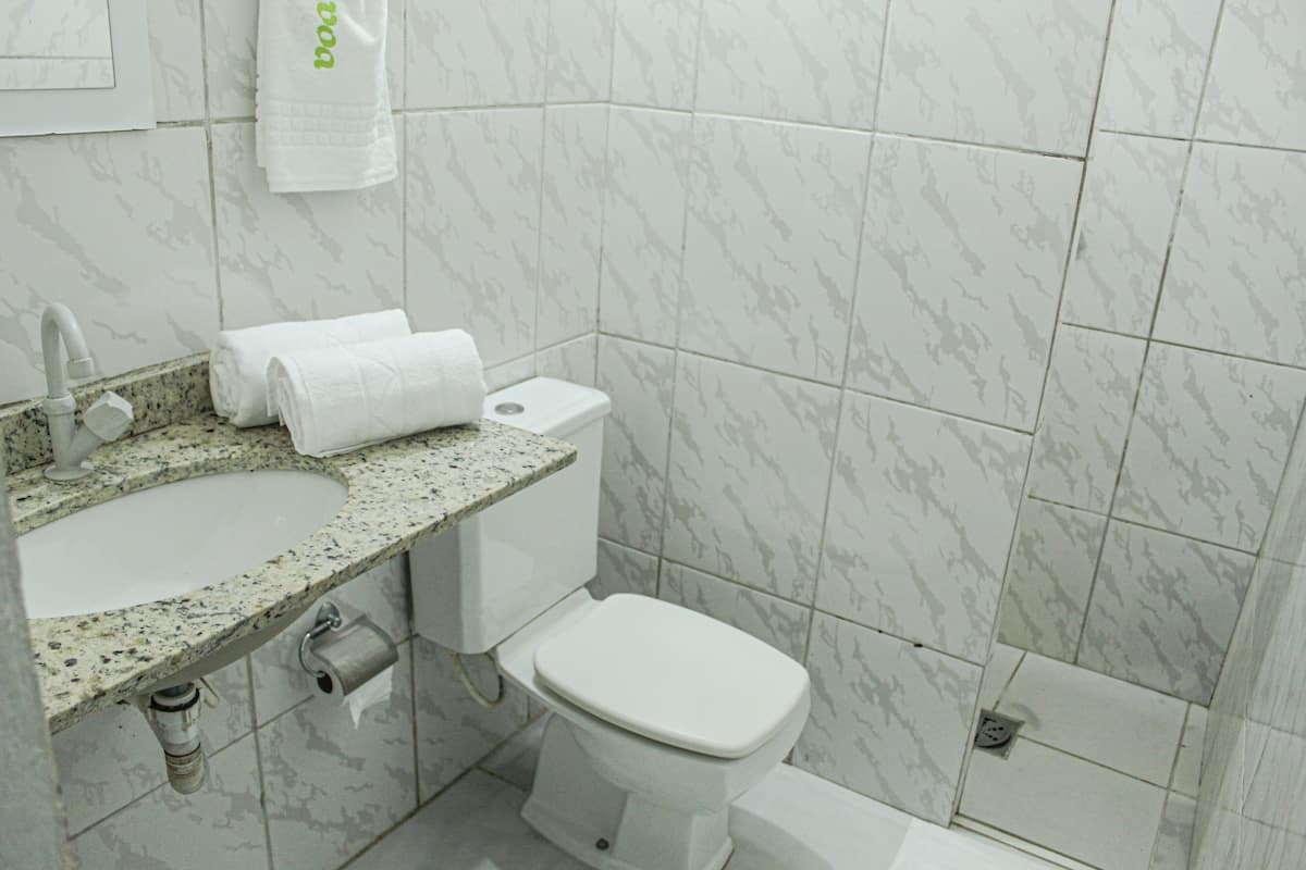 A bathroom with a sink, toilet, and a marble-tiled wall.