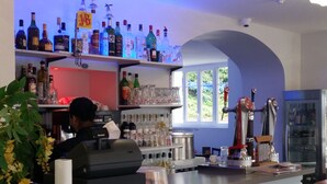 Zona de bar con barra, estantes llenos de botellas de licor y vistas al exterior a través de una ventana.