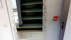 Una escalera con un papel tapiz decorado y una caja roja de emergencia.