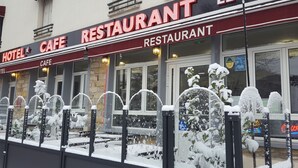 Un hotel con cafetería y restaurante, con amplias ventanas y una entrada cubierta de nieve.