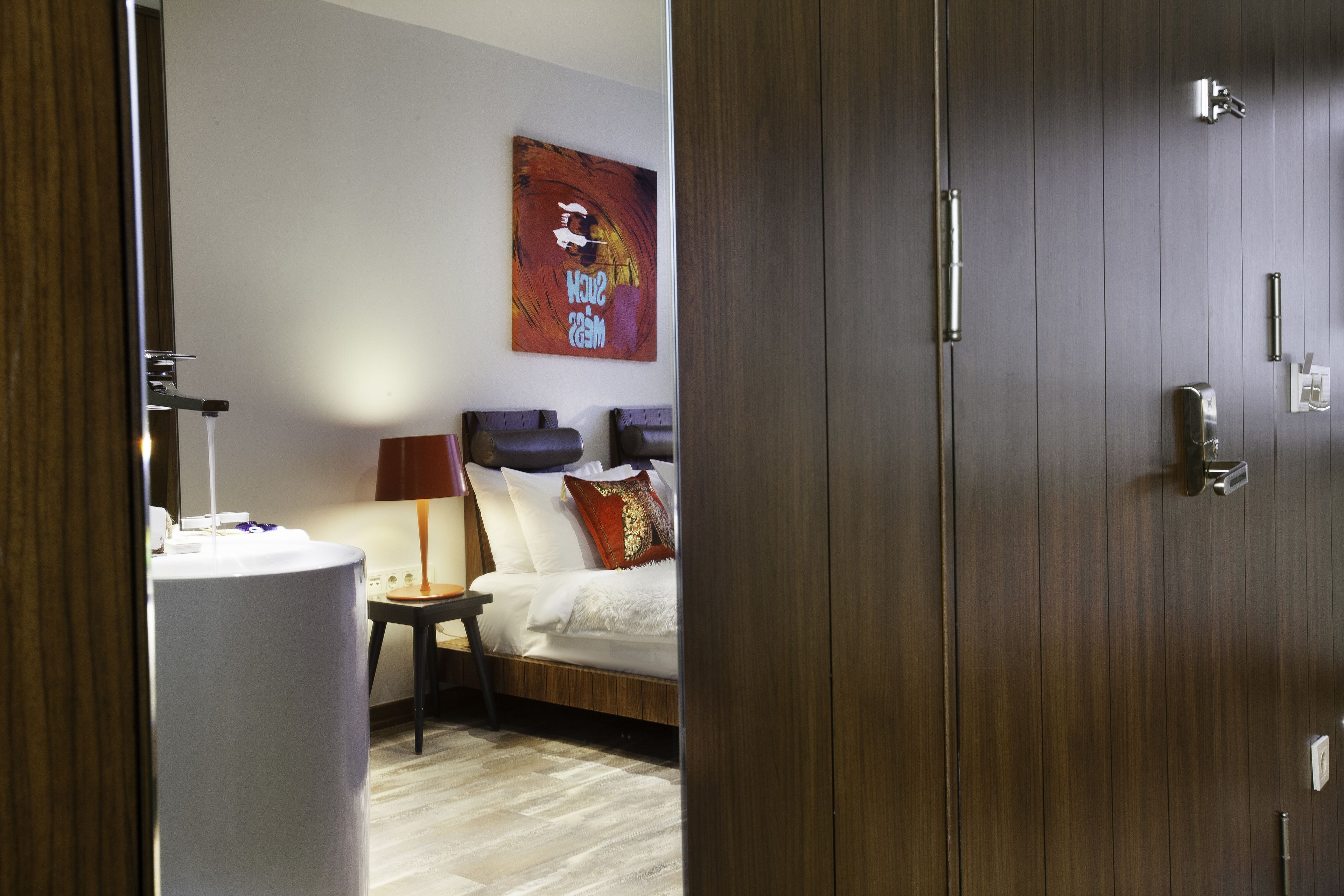 Een hotelkamer met een bed, nachtkastje en een schilderij aan de muur.