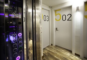 Ascensore con pannello di controllo e corridoio con porte numerate 103 e 502.