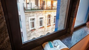 Una ventana con vista al exterior de un edificio, un libro y una brújula sobre el alféizar.