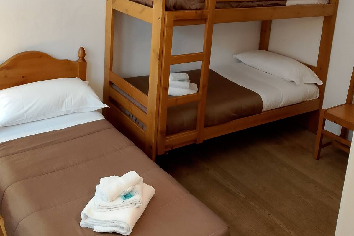 A bunk bed room with a single bed and a small table.