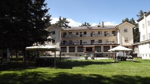 A multi-story building with balconies, a covered outdoor seating area, and a grassy courtyard.