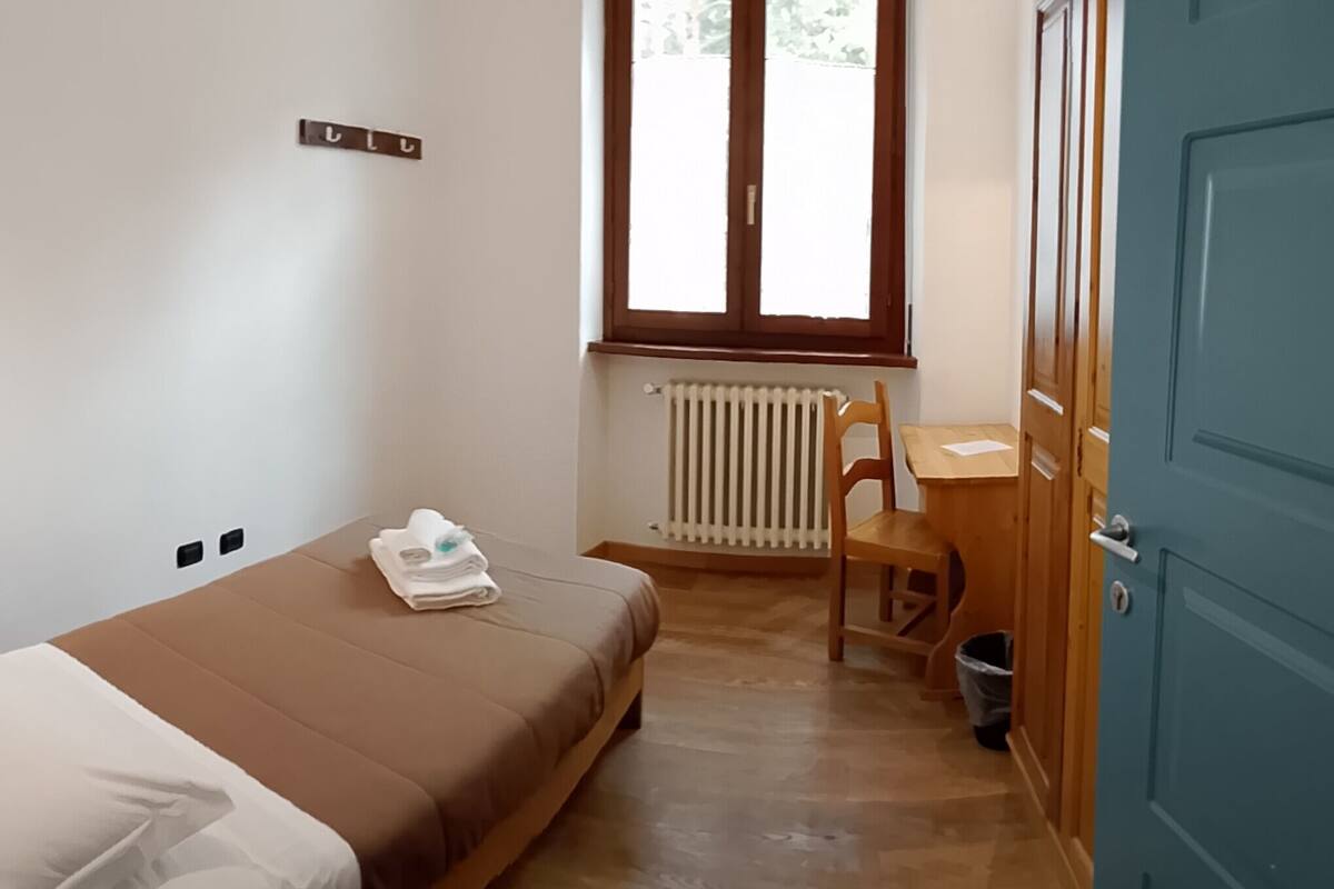 A small, tidy room with a bed, a desk, and a chair.
