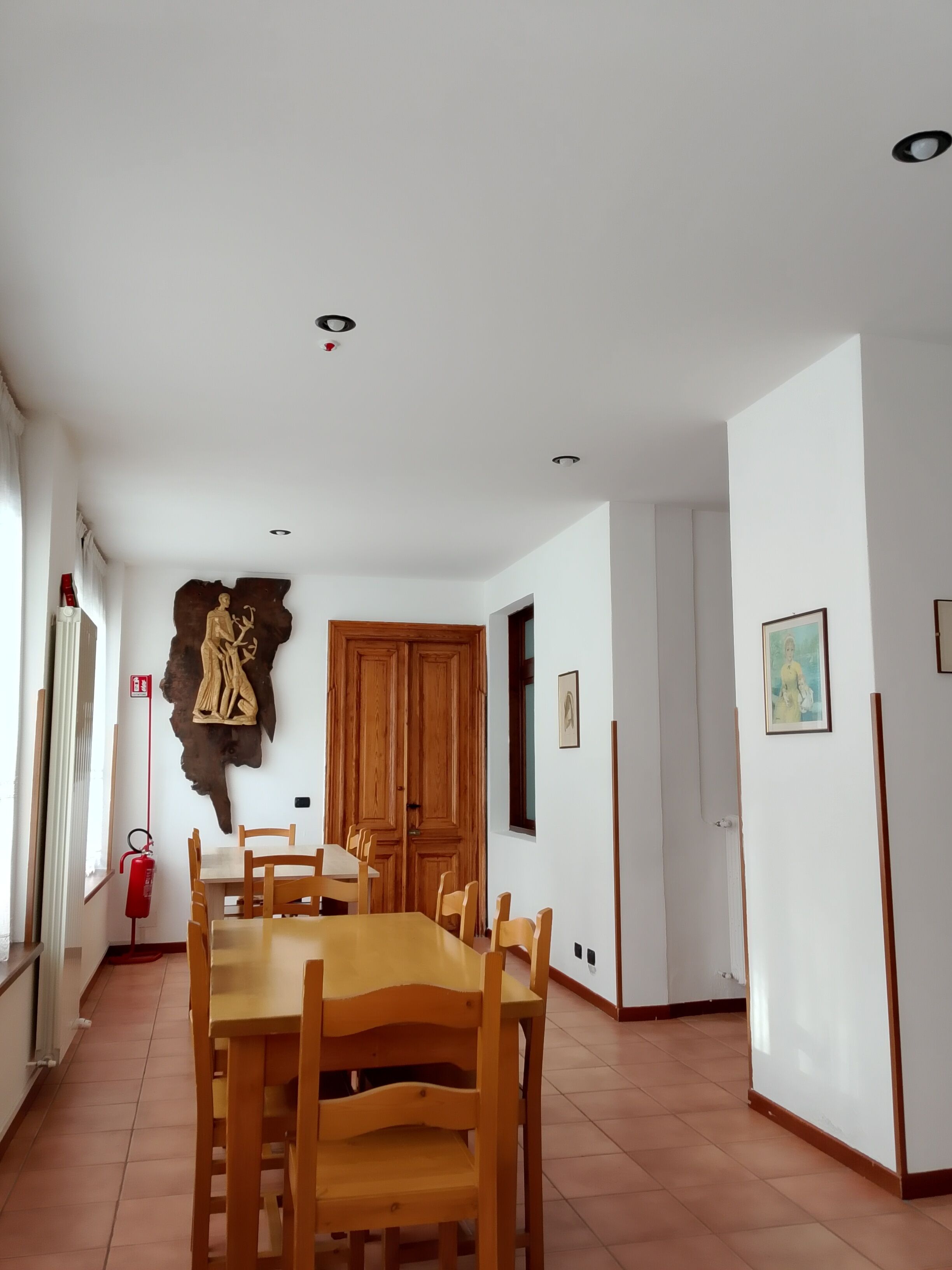 Un coin repas avec une table et des chaises en bois, une peau d’animal accrochée au mur et une porte en bois.