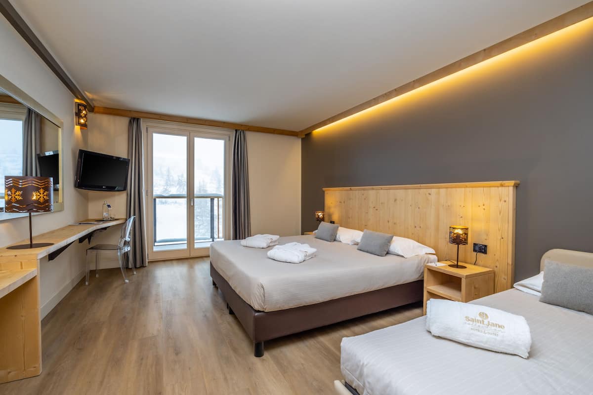 A modern hotel room with a large bed, a desk, a TV, and a view of the outdoors.