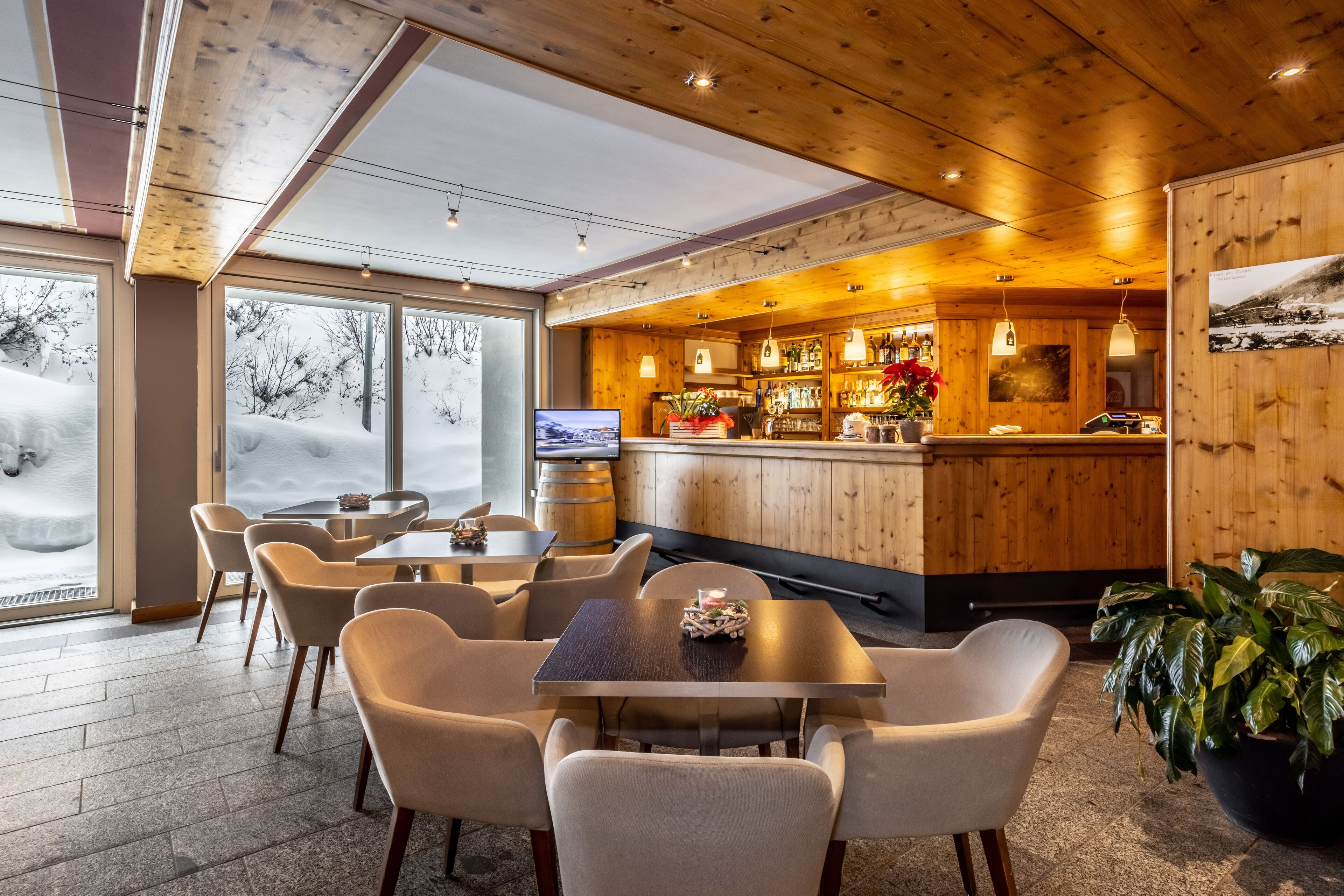 Un restaurant chaleureux avec des murs en bois et un coin bar. On y trouve plusieurs tables et chaises pour prendre ses repas.