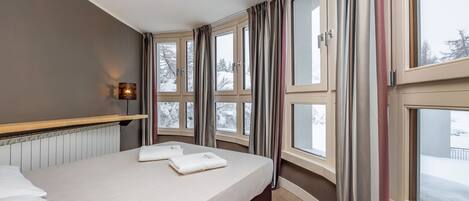 Una habitación de hotel con una cama grande, múltiples ventanas y una luz nocturna en la pared.