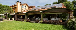 A building with a green lawn, a covered patio area, and solar panels on the roof. - Hotel La Bergamina (Arcore)