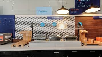 A modern breakfast bar with a geometric backsplash, labeled signs for hot food and Express Start Breakfasts, and a wooden counter design.