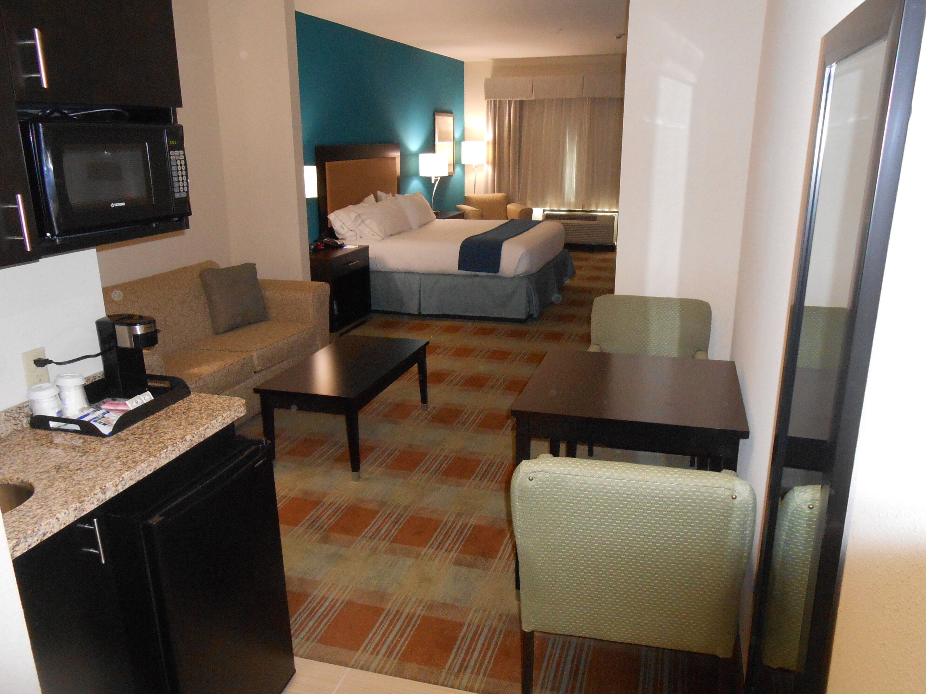 Une chambre d’hôtel équipée d’une kitchenette, d’un lit, d’un canapé, d’une table à manger et d’une chaise.
