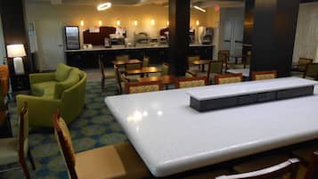 Un comedor de hotel con una larga mesa, sillas y una máquina de café.
