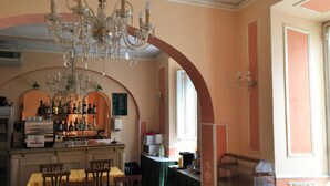 Ein Restaurant mit Barbereich, Tischen, Stühlen, einer Kristallleuchter und einer Speisekarte.