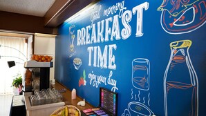 A breakfast area with a wall mural, a coffee machine, and a fruit basket. - Hotel le Beffroi (Dreux)