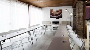 A conference room with a long table, white chairs, a radiator, and a painting on the wall. - Hotel le Beffroi (Dreux)