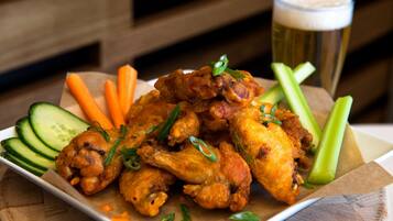 A plate of chicken wings with celery and carrots, accompanied by a glass of beer.