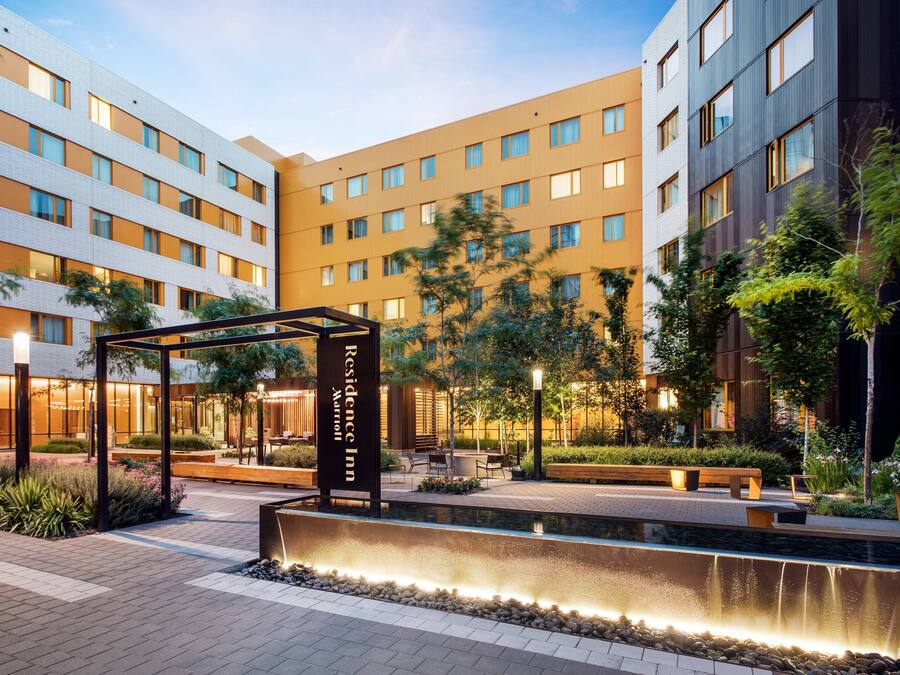 Une cour d’hôtel agrémentée d’un élément aquatique, de coins salon et d’un panneau indiquant l’emplacement du « Residence Inn ».