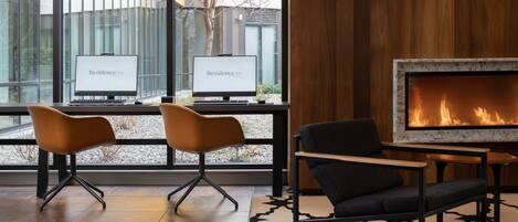 Un vestíbulo moderno con dos monitores de computadora, una chimenea y dos sillones.