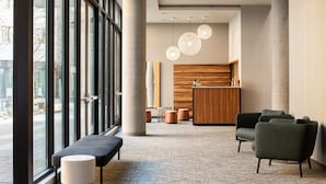 Un hall d’entrée moderne doté de grandes fenêtres, d’un comptoir de réception et d’espaces aménagés pour s’asseoir.