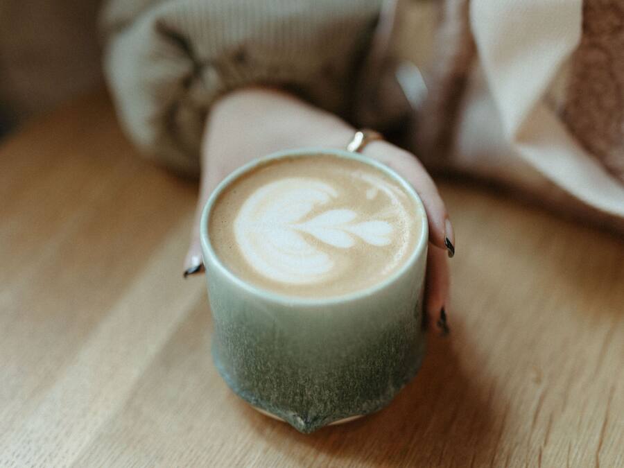 A cup of coffee with latte art on a wooden table.