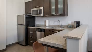 A modern kitchen with stainless steel appliances, a granite countertop, and brown cabinetry.