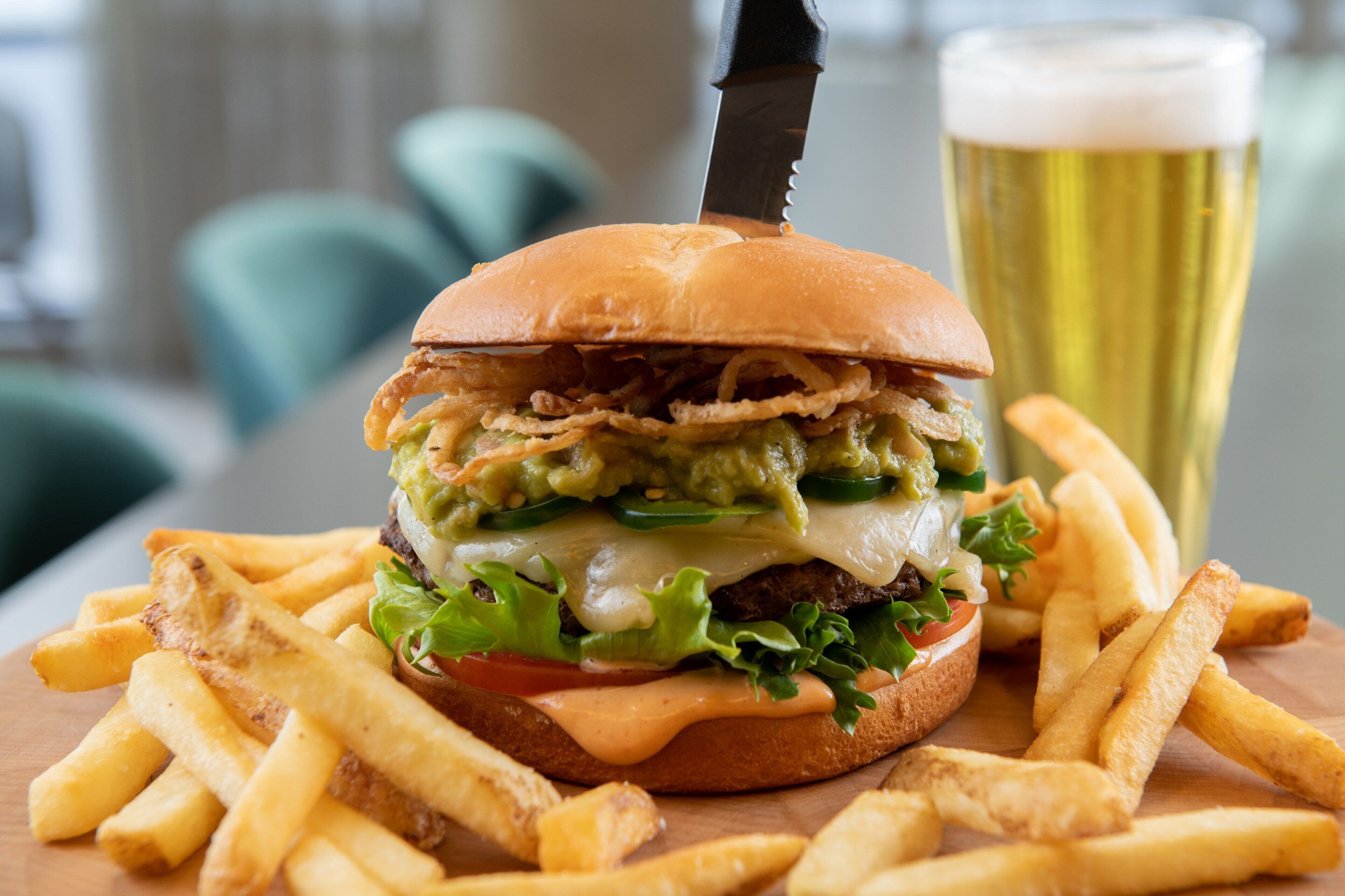 A burger with fries and a glass of beer on a wooden table.
