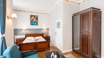A bedroom with a wooden bed, a blue armchair, a wardrobe, and a painting on the wall.