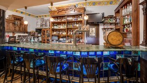 A bar area with a bar counter, stools, shelves with bottles, and a television. - Małopolanka & Spa (Krynica-Zdroj)