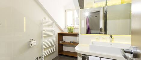 A modern bathroom with a toilet, sink, mirror, and towel rack.
